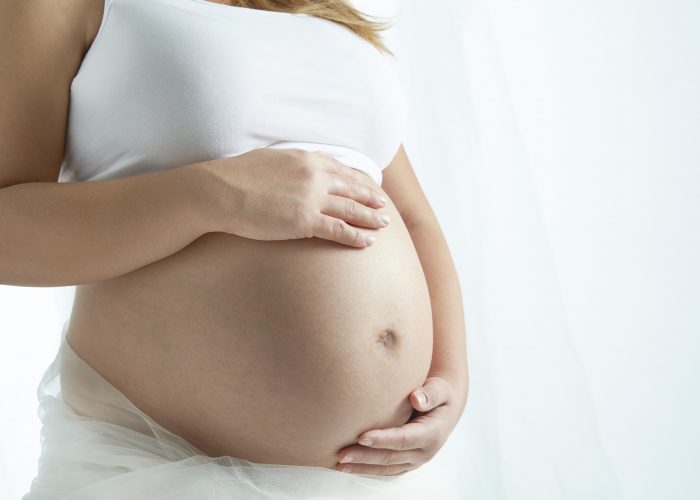 Pregnant woman cradling unborn child
